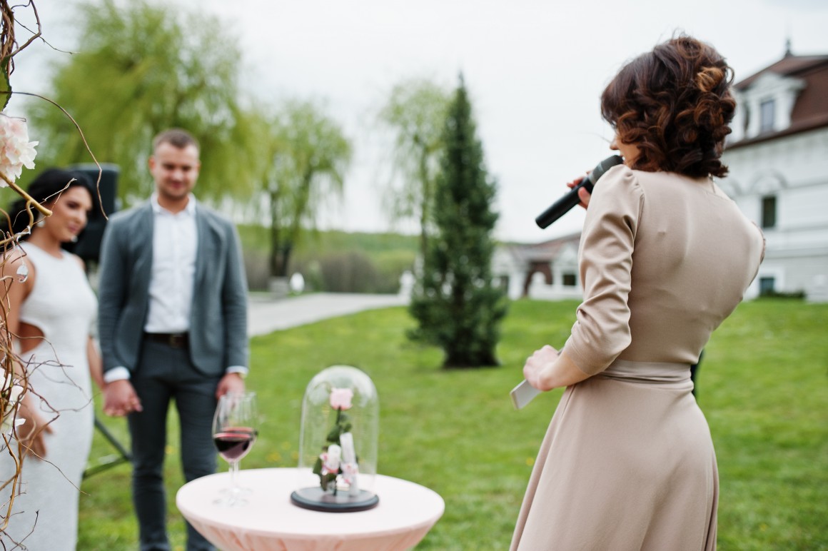 Woman giving speech to bride and groom at outdoor wedding